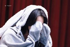 a woman wrapped in a towel covering her face