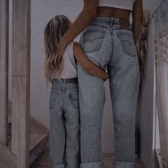 the mother and daughter are standing at the bottom of the stairs, both wearing jeans