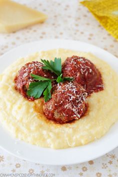 two meatballs covered in sauce and parsley on top of mashed potato grits