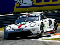 a white porsche racing car driving on a race track