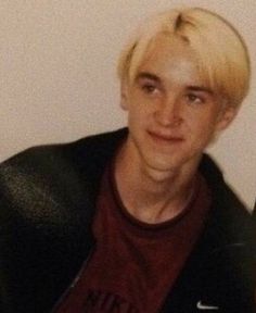 a young man with blonde hair wearing a black jacket