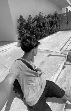 black and white photograph of a person sitting on the sidewalk