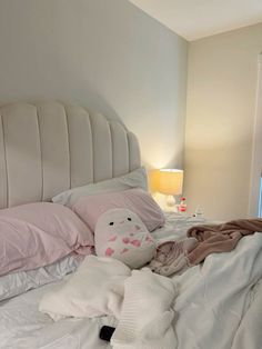 an unmade bed with pillows and blankets on top of it, next to a lamp