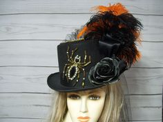 Ladies Black top hat with two large beaded and rhinestone spiders with black roses, black and orange ostrich feathers and a black bustle and train on the back. This is a black hard felt costume grade top hat. PLEASE MEASURE YOUR HEAD! This hat is 22.5" for the inside circumference. I will include a peel and stick hat sizer if you need it smaller, but I cannot make it larger. Please keep this in mind when deciding. Check out my other items in my shop. Thank you for stopping by. All sales are final! Please keep that in mind when purchasing. Check out my other hats and fascinators.  https://www.etsy.com/shop/MsPurdy I ship many times a week. This hat will ship priority mail within the U.S. with tracking number. Black Top Hat For Halloween, Black Themed Top Hat For Halloween, Black Halloween Themed Top Hat, Adjustable Black Top Hat For Halloween, Witchy Black Top Hat For Halloween, Themed Black Top Hat For Halloween, Black Whimsical Costume Accessories For Party, Whimsical Black Costume Accessories For Party, Whimsical Black Mini Hats For Halloween