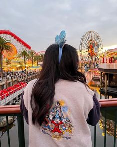 a woman is looking out over the water at an amusement park