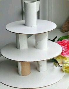 three tiered white cake stand with flowers on the side and a teddy bear next to it