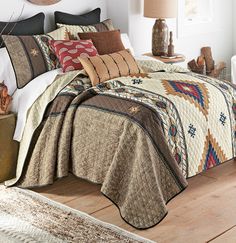 a bedroom with a bed covered in a quilt and pillows on top of the bed