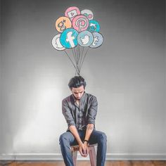 a man sitting on top of a stool with balloons above his head