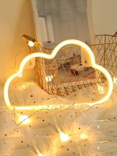 there is a basket with lights in the shape of a cloud on top of a bed