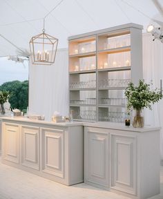 a kitchen with white cabinets and flowers in vases on the counter top next to it