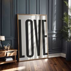 a poster with the word love on it in front of a wooden table and lamp