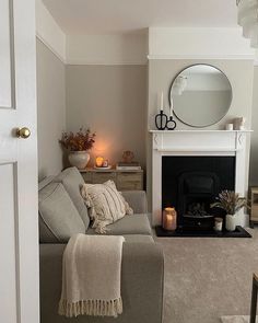 a living room filled with furniture and a fire place in front of a mirror on the wall