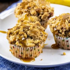 three muffins on a white plate with caramel drizzle and bananas