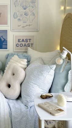 a bed with blue and white comforters, pillows and pictures on the wall above it