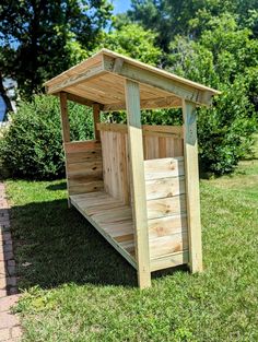 a small wooden shelter sitting on top of a lush green field