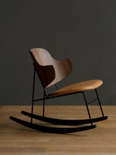 a wooden rocking chair sitting on top of a hard wood floor next to a gray wall