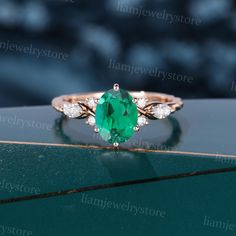 an emerald and diamond ring sitting on top of a table