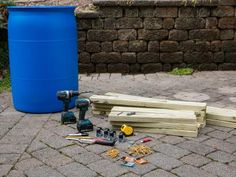 tools are laying on the ground next to a blue barrel