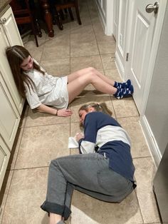 two people laying on the floor in a kitchen