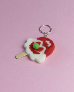 a red and white lollipop keychain with a green apple on it