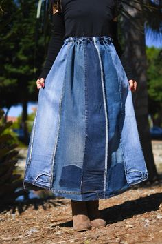 a woman in a black top and blue skirt is standing on the ground with her hands in her pockets