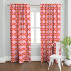 a white chair sitting in front of a window with pink and orange curtains on it