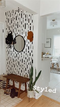 a room with a bench, mirror and plant in the corner on the wall next to it