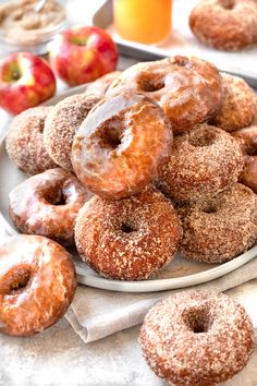 a pile of donuts sitting on top of a white plate next to an orange juice