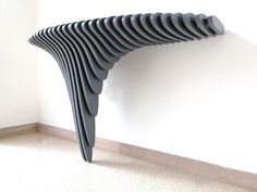 a long black object is leaning against the wall and it's curved like a wave