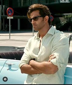 a man standing next to a car with his arms crossed