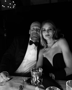 a man and woman sitting at a table in front of each other, posing for the camera