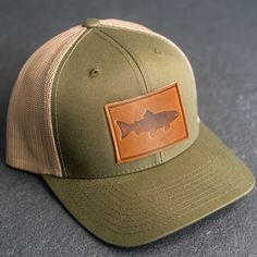 Wear your new Leather Patch Trucker Style Hat out fishing or anywhere! All hats ship for free within the USA! SPECS *Leather Patch Color Options: Natural Dublin (Light) or Nut Brown Dublin (Dark) *Hat Color Options: Choose from Navy/White, Charcoal, or Green/Khaki *All of our products are made to order by hand in McKinney, TX MATERIALS *REAL HORWEEN LEATHER: Premium Full-Grain Leather. oEach patch is one-of-a-kind and made from part of a whole hide of leather. There will be unique variation from Brown Trucker Hat With Short Brim For Outdoor Activities, Adjustable Flat Brim Trucker Hat For Fishing, Khaki Fishing Cap, Khaki Cap For Fishing, Adjustable Khaki Hunting Hat, Adjustable Khaki Hat For Hunting, Adjustable Green Hats For Fishing, Brown Snapback Fishing Hat, Brown Snapback Hat For Fishing