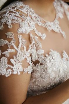 the back of a woman's wedding dress with white flowers on it and lace