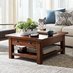 a living room with a couch, coffee table and two planters on the end tables