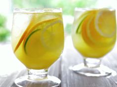 two glasses filled with lemonade sitting on top of a wooden table