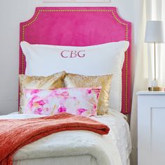 a bed with pink headboard and gold pillows