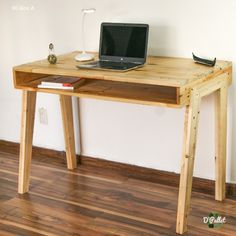 a laptop computer sitting on top of a wooden desk next to a book and lamp