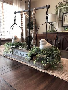 two white birds sitting on top of a wooden table next to a sign that says hello summer