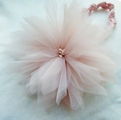 a pink and white flower on a light blue cloth with a beaded headband