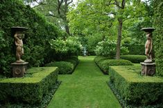 an outdoor garden with hedges and statues