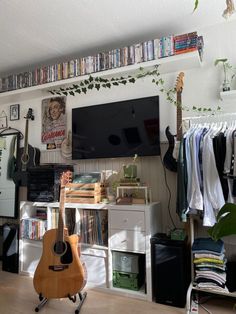 a guitar is sitting in front of a television and bookshelf filled with dvds