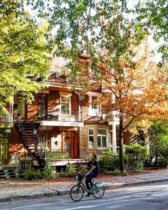 a person riding a bike down the street in front of a house on a sunny day