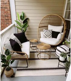 two wicker chairs sitting on top of a porch next to a potted plant