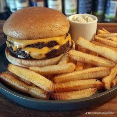 a cheeseburger and french fries on a plate with a small bowl of ranch dressing