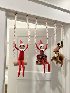 three elf dolls hanging from the ceiling with candy canes