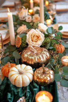 a long table with candles, flowers and pumpkins on the centerpiece is decorated with greenery