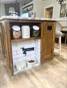 an open cabinet in the middle of a kitchen with two bowls and one bowl on it