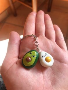 two eggs and an egg on a keychain in the palm of someone's hand