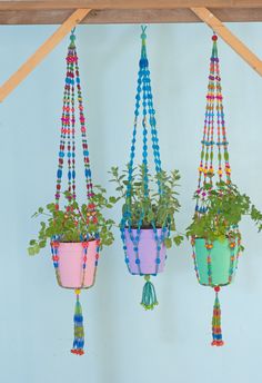 three hanging planters with plants in them and beads on the bottom one is blue