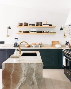 a kitchen with marble counter tops and black cabinets, along with open shelving above the stove